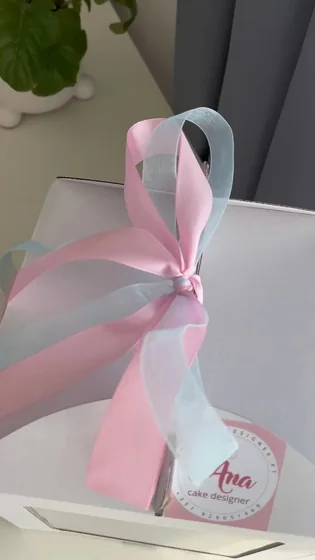 Caixa de bolo com laço cor-de-rosa, pronta para a festa
